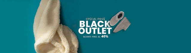 Stivaletti invernali EMU Australia in suede grigio con fodera in pelliccia, appoggiati su sfondo verde petrolio accanto a un morbido tessuto in lana.