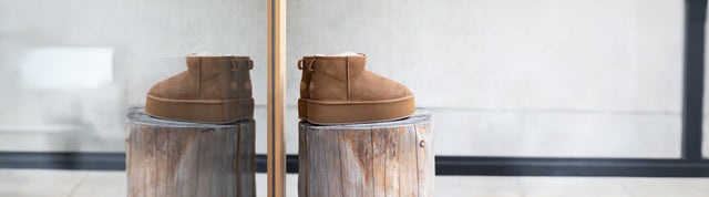 Stivaletti EMU Australia Stinger Flatform da donna in shearling marrone, su ceppo di legno con riflesso sul vetro.