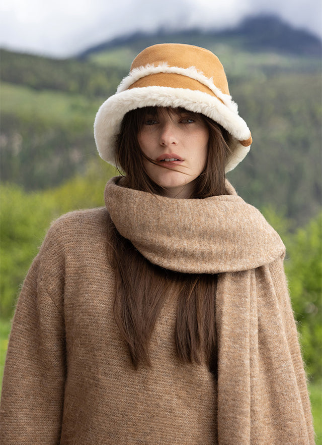 Look lifestyle EMU Australia con cappello in montone e outfit invernale, sfondo montagna