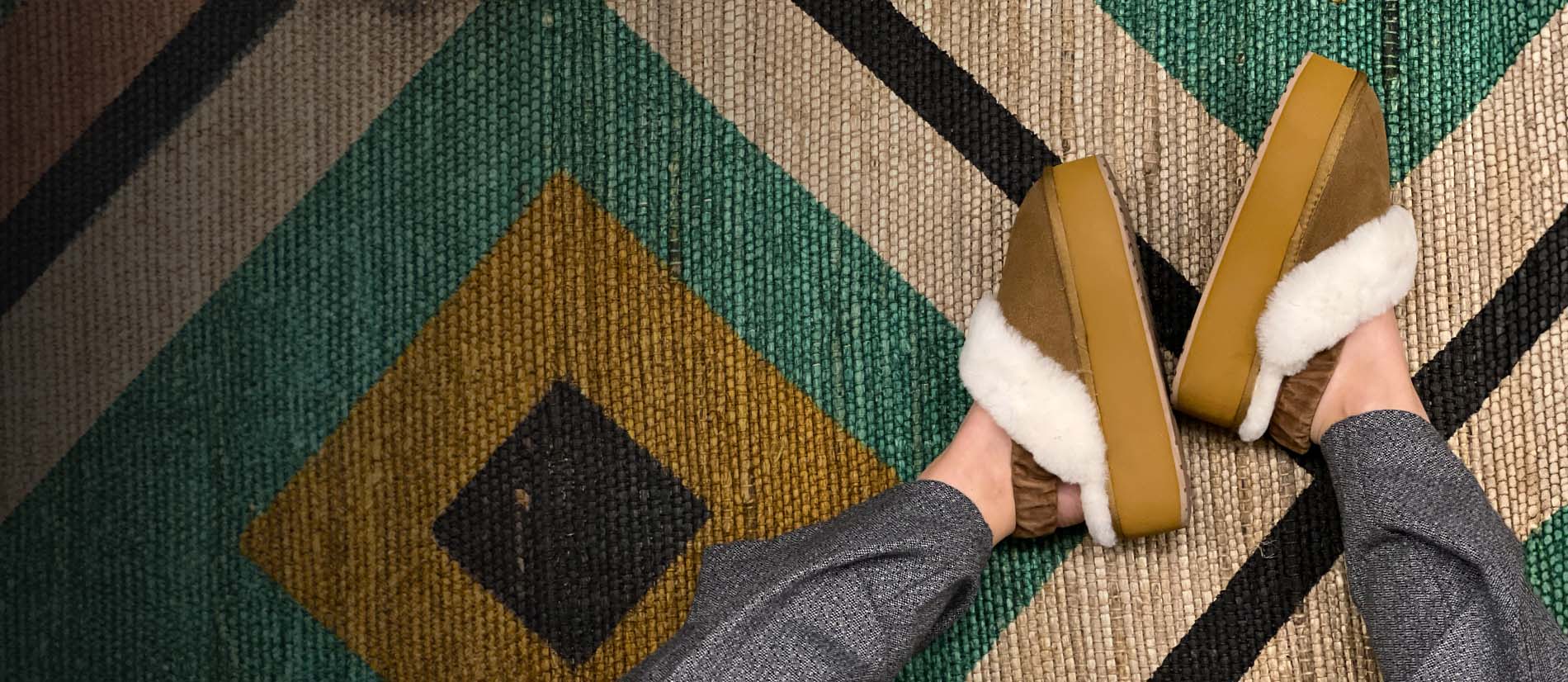 dettaglio_donna_che_indossa_ciabatte_con_pelo_emu_australia_hartz_su_tappeto_colorato