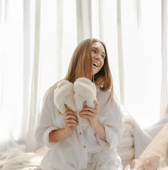 Donna con pantofole EMU Mayberry in montone naturale bianco, modello aperto con fascia incrociata morbida e avvolgente per uso casa