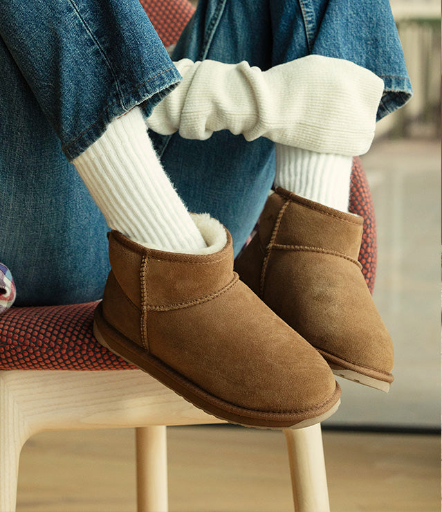 Donna con stivaletti Stinger EMU Australia marroni indossati con calze chiare e jeans.