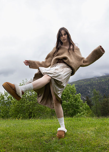 Donna con stivaletti EMU Australia in shearling marrone, look invernale con gonna e maglione oversize   