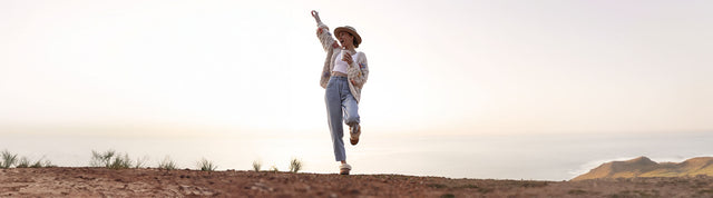 donna che esulta in mezzo alla natura e che indossa ciabatte con pelo emu australia jolie camel