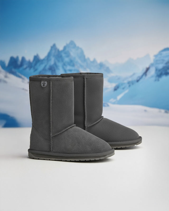 Donna seduta vicino a una finestra che indossa stivaletti EMU Australia Stinger grigi in un ambiente caldo e accogliente.